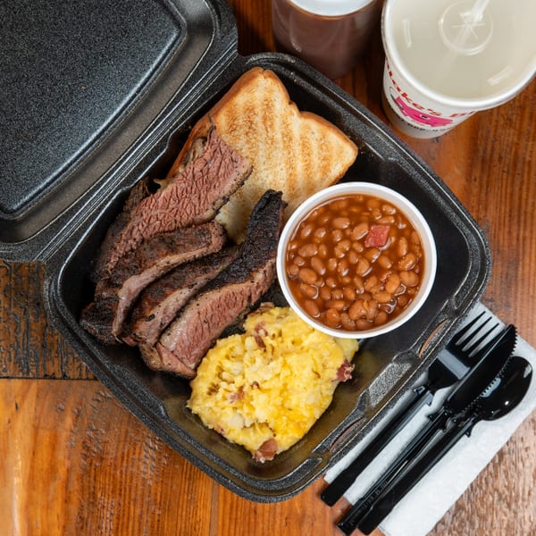 Blake's Barbecue brisket plate with baked beans, mashed potatoes, and Texas toast in a to-go container.