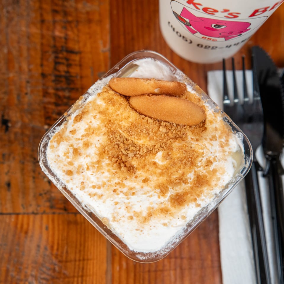 Blake's Barbecue banana pudding with vanilla wafers and crumbles, next to a branded cup.